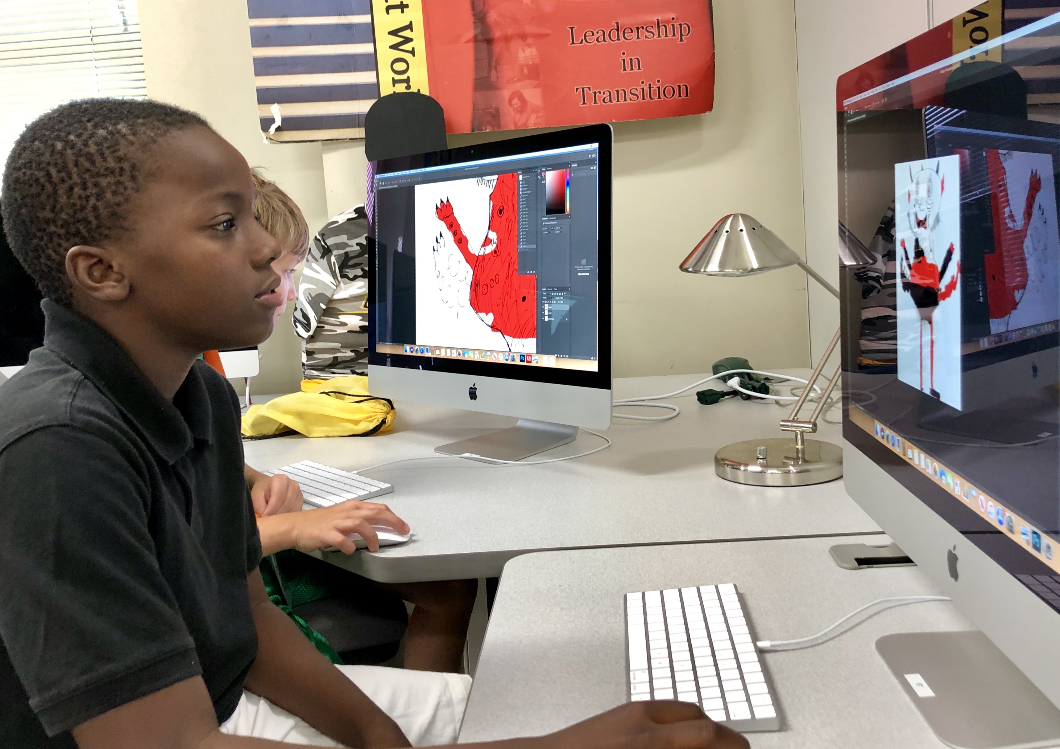 Students working on coloring their monster drawings on the computer.