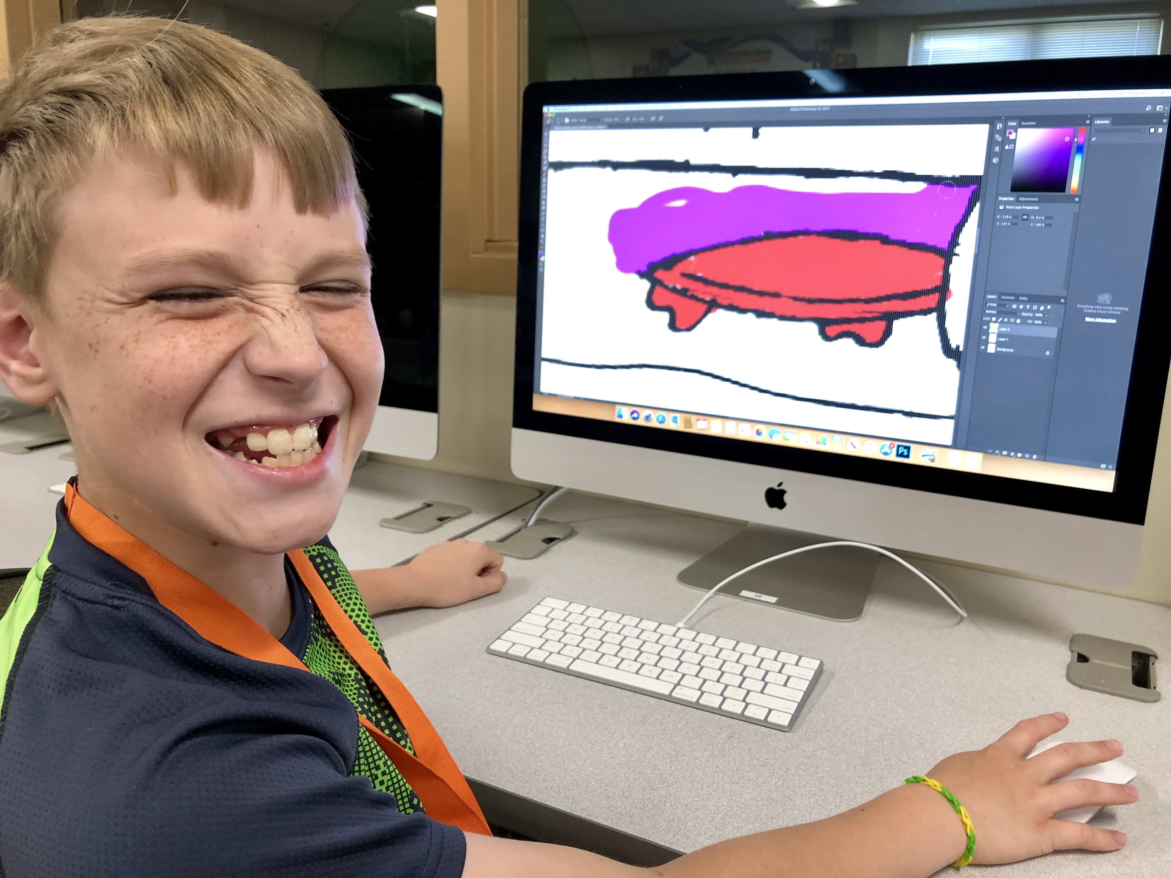 A male student smiling with his artwork on computer.