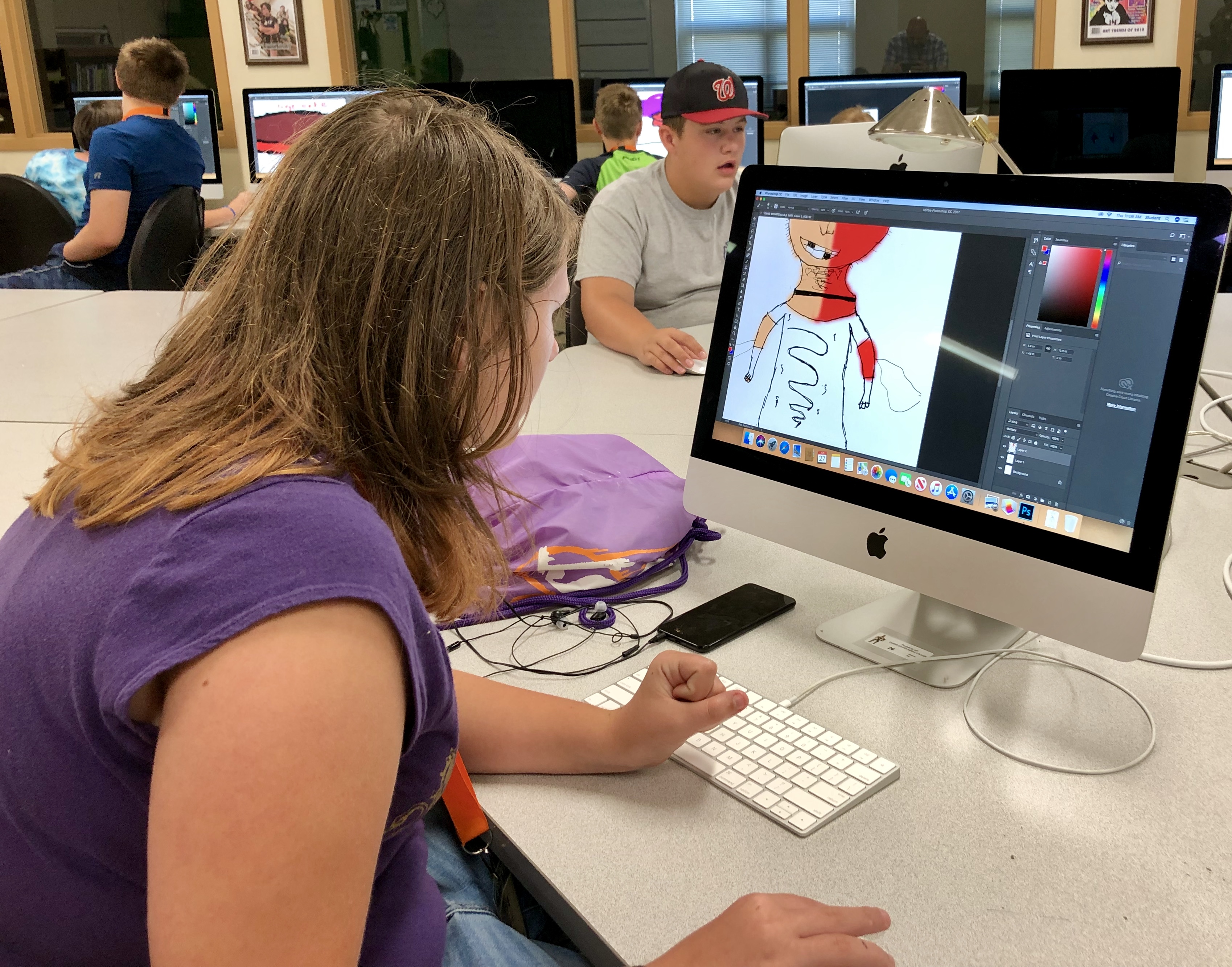 Students working on coloring their monster drawings on the computer.